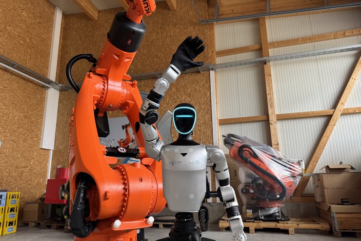 Ein menschenähnlicher grauer Roboter winkt in die Kamera.