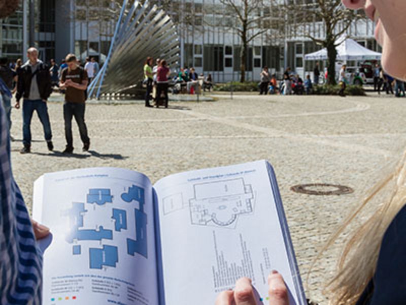 Studieninteressierte Person betrachtet Campusplan der Hochschule Kempten während eines Kennenlernangebots auf dem Campus.