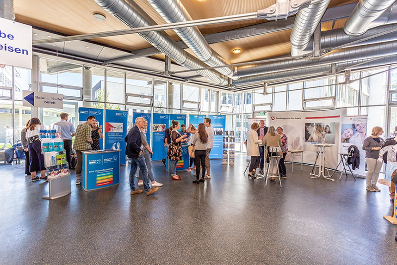 Besucherinnen und Besucher informieren sich an Messeständen auf der Allgäuer Hochschulmesse an der Hochschule Kempten.